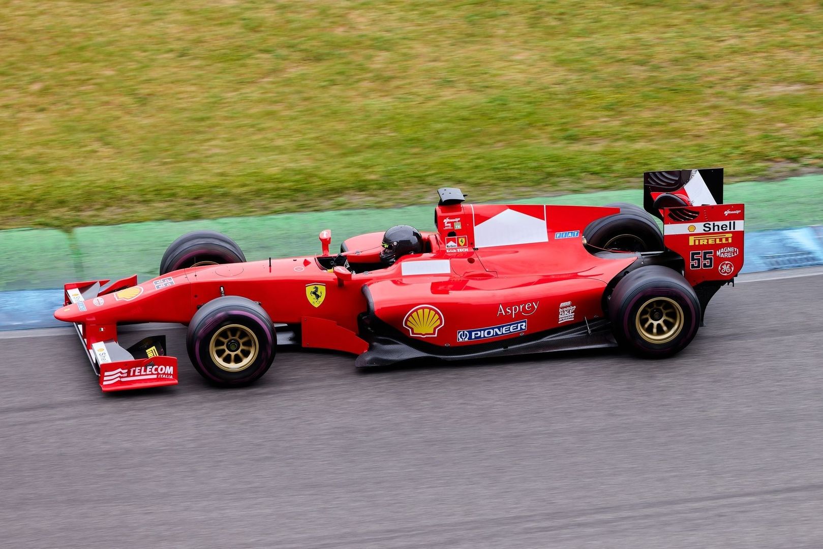 Rode Formule 1-auto rijdt langs een groene uitloopstrook
